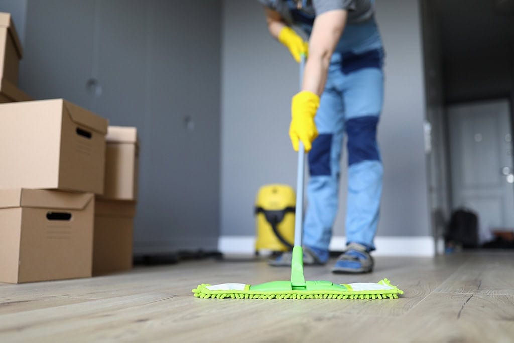 Female mopping hardwood floors to prepare for a move-out