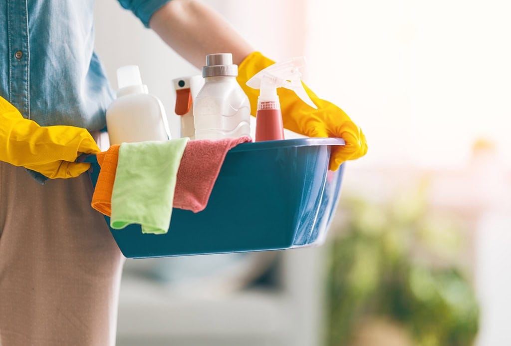 woman getting ready to clean her house with cleaning supplies
