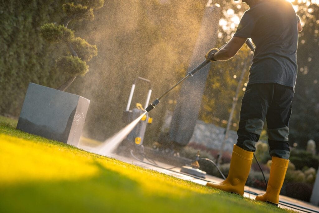 a gardener cleaning a patio with a pressure washer